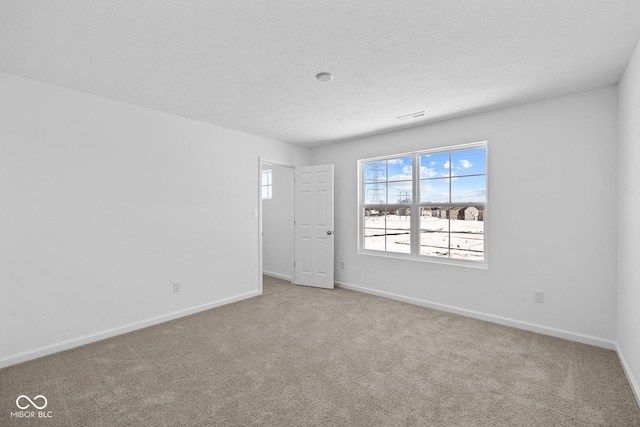 empty room featuring carpet, visible vents, baseboards, and a textured ceiling