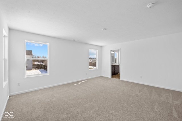 carpeted spare room with a textured ceiling and baseboards