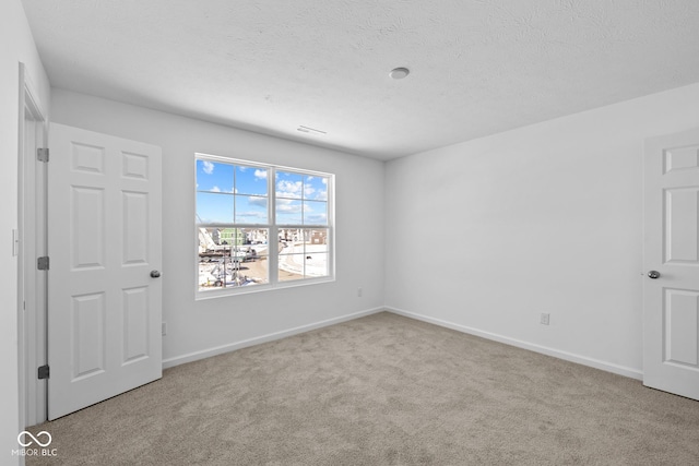 empty room with a textured ceiling, carpet flooring, and baseboards