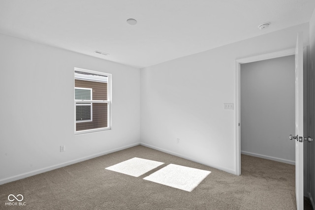 carpeted spare room featuring visible vents and baseboards