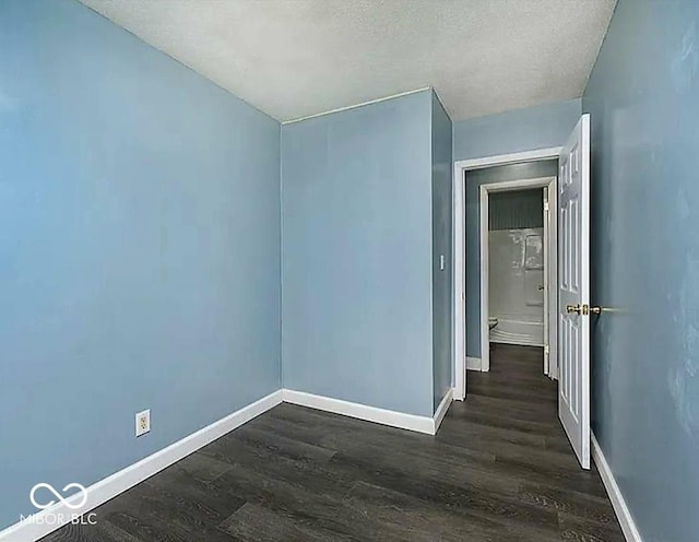 spare room featuring dark wood-type flooring, baseboards, and a textured ceiling