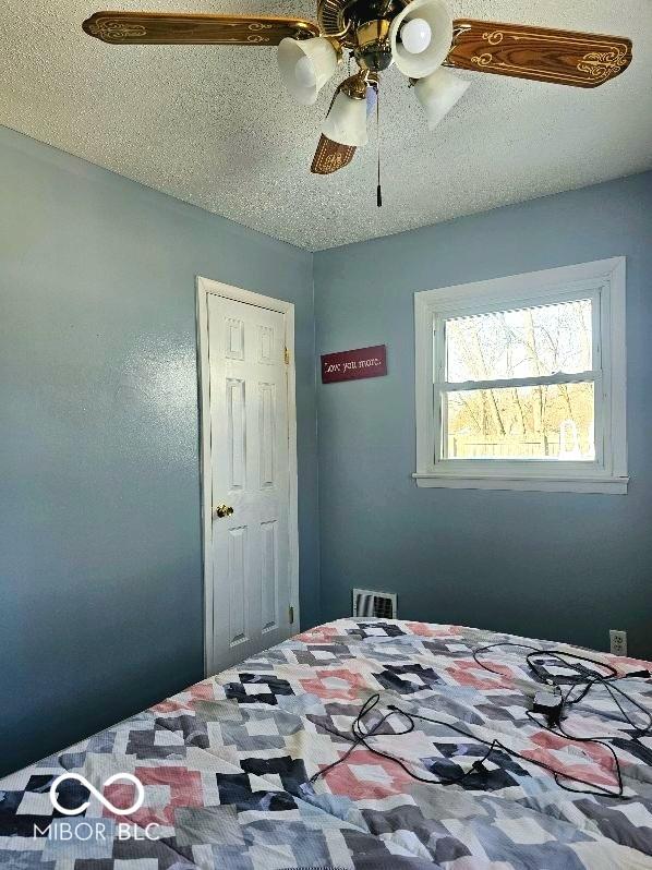 bedroom featuring a textured ceiling, ceiling fan, and visible vents