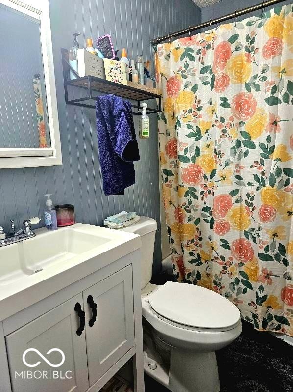 full bath with toilet, curtained shower, vanity, and wallpapered walls