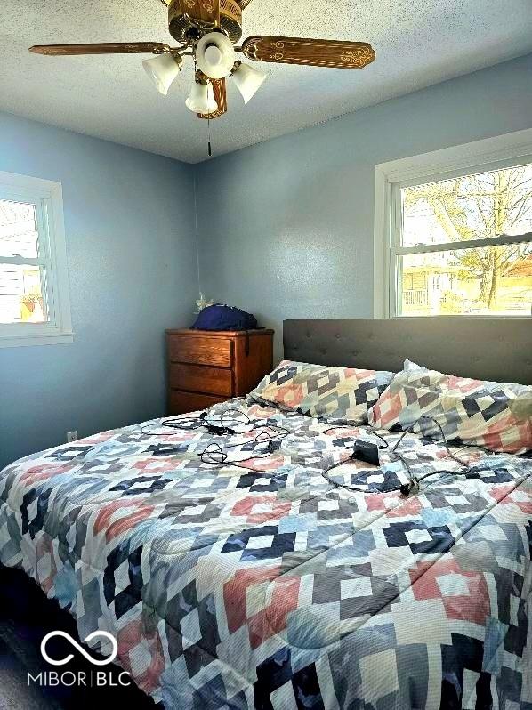 bedroom with ceiling fan, multiple windows, and a textured ceiling