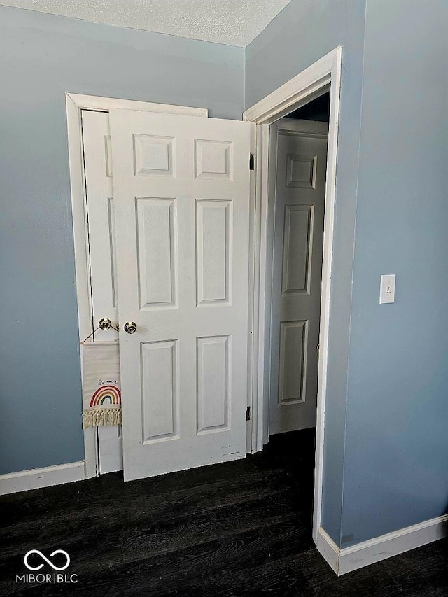 corridor with baseboards and dark wood-style floors