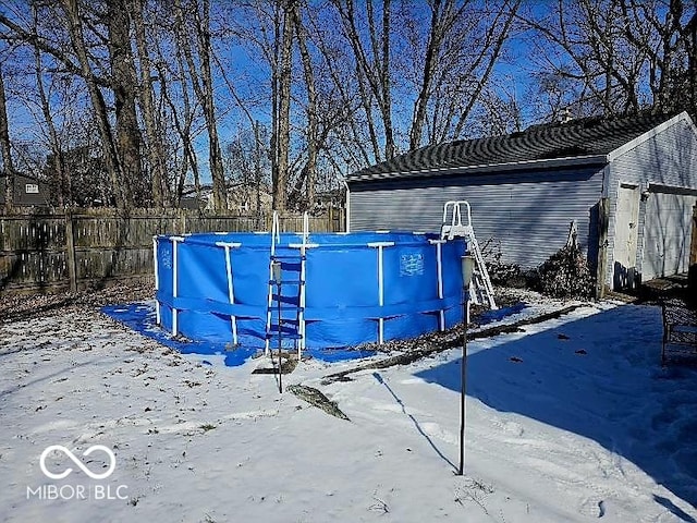 snow covered structure with an outdoor pool and fence