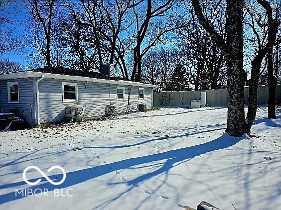 yard covered in snow featuring cooling unit and fence