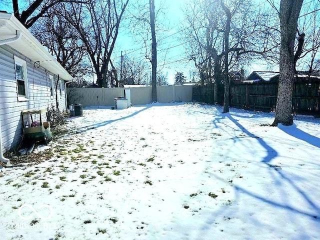 snowy yard featuring a fenced backyard