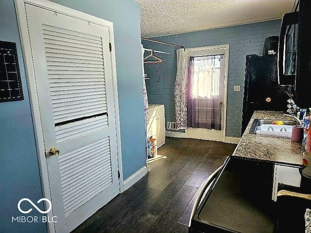 kitchen featuring a sink, hardwood / wood-style flooring, baseboards, and a textured ceiling