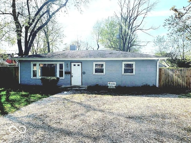 single story home featuring a shingled roof, a chimney, and fence