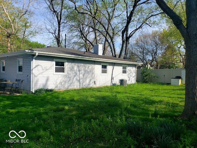 exterior space featuring a chimney, fence, a yard, and central AC