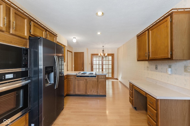 kitchen featuring fridge with ice dispenser, black microwave, an inviting chandelier, oven, and pendant lighting