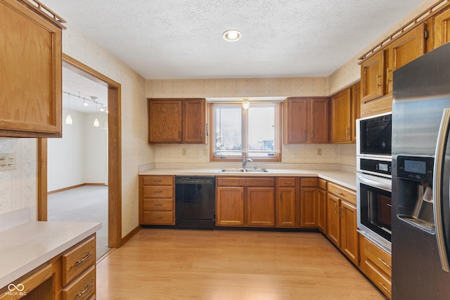 kitchen featuring sink, light hardwood / wood-style floors, a textured ceiling, track lighting, and appliances with stainless steel finishes