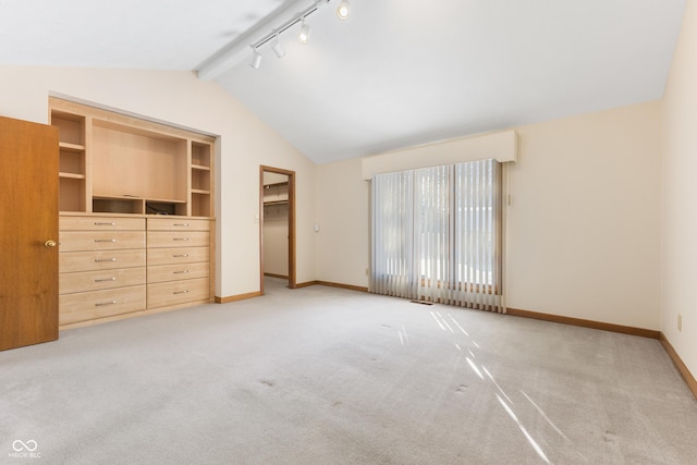 unfurnished bedroom featuring vaulted ceiling with beams, light colored carpet, a walk in closet, and a closet