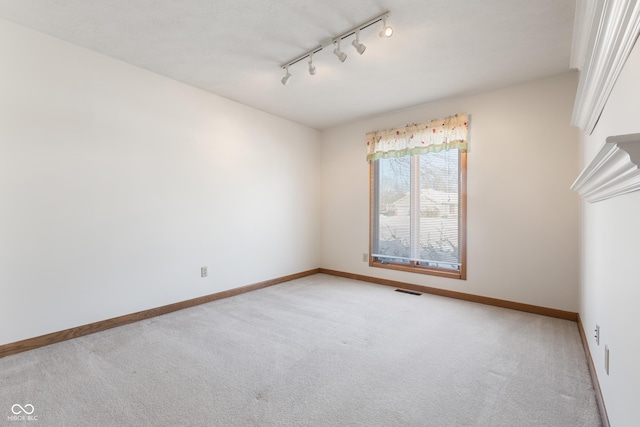 carpeted spare room featuring track lighting