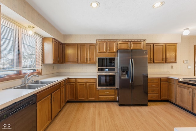 kitchen featuring black appliances, sink, and light hardwood / wood-style flooring