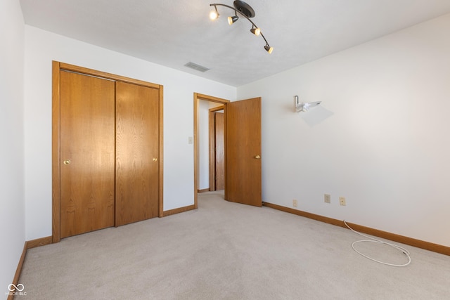 unfurnished bedroom featuring light carpet and a closet