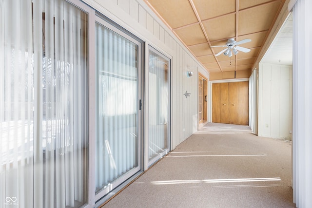 corridor featuring light carpet and wooden walls