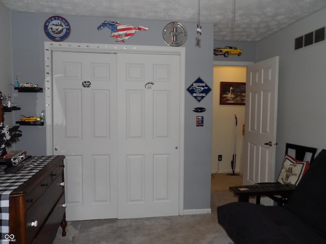 interior space featuring a textured ceiling, light colored carpet, and a closet