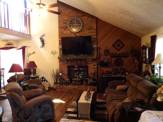 living room with hardwood / wood-style floors, wood walls, ceiling fan, a wealth of natural light, and lofted ceiling