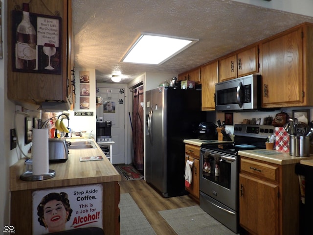 kitchen featuring appliances with stainless steel finishes, light hardwood / wood-style floors, and a textured ceiling