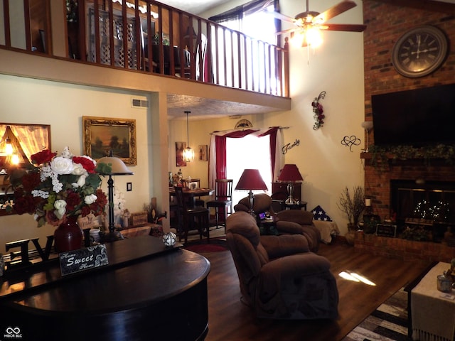 living room with wood-type flooring, a high ceiling, ceiling fan, and a fireplace