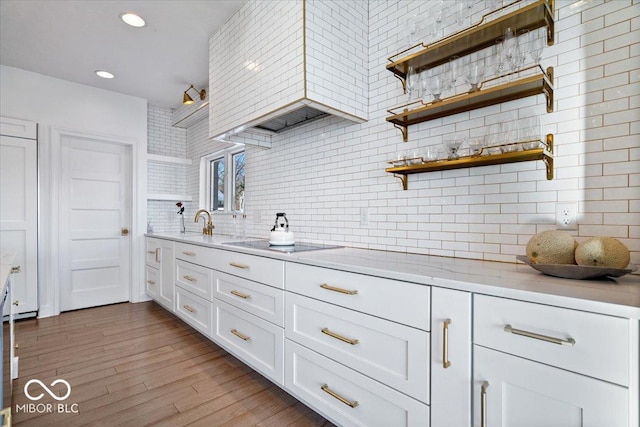 kitchen featuring white cabinetry, light stone counters, light hardwood / wood-style flooring, decorative backsplash, and electric stovetop