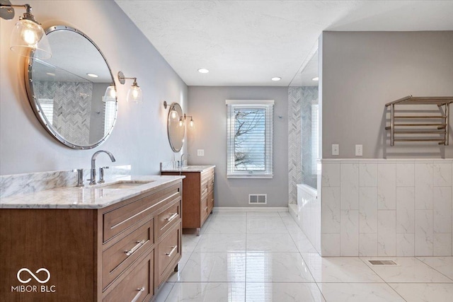 bathroom featuring a washtub, a textured ceiling, and vanity