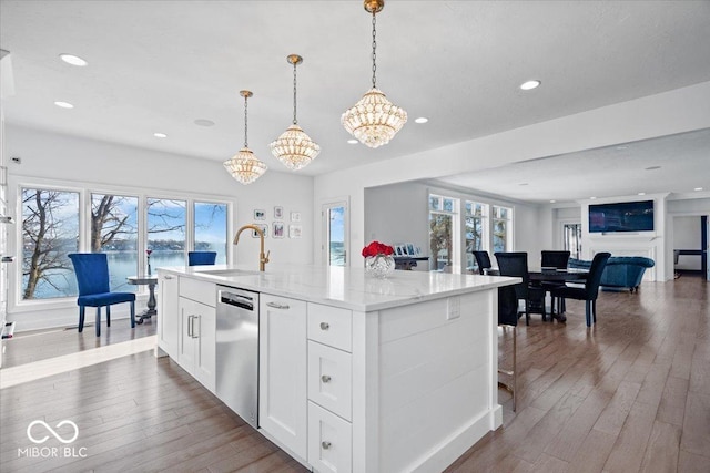 kitchen featuring dishwasher, white cabinetry, a kitchen island with sink, and sink