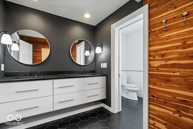 bathroom with tile patterned flooring, vanity, toilet, and tile walls