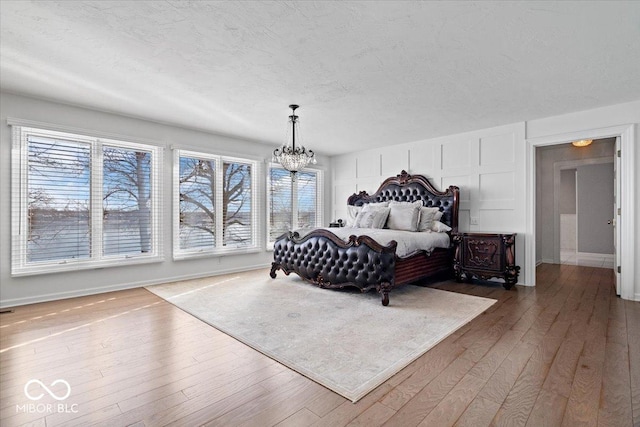 bedroom with wood-type flooring, a textured ceiling, and a notable chandelier