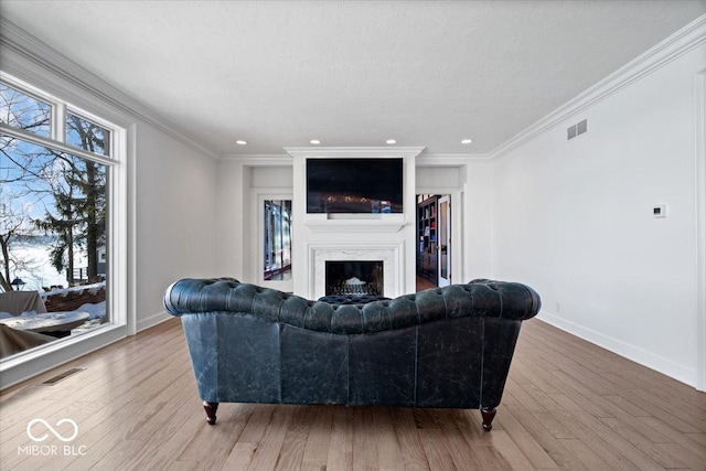 living room with light hardwood / wood-style flooring, a high end fireplace, and ornamental molding