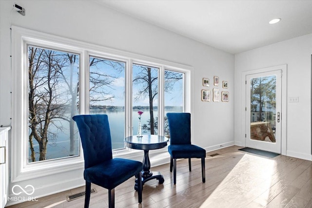 living area with a water view and light hardwood / wood-style flooring