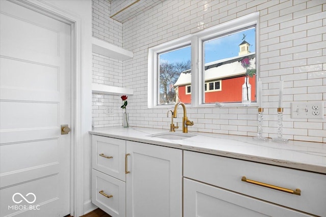 interior space featuring light stone counters, sink, and white cabinets