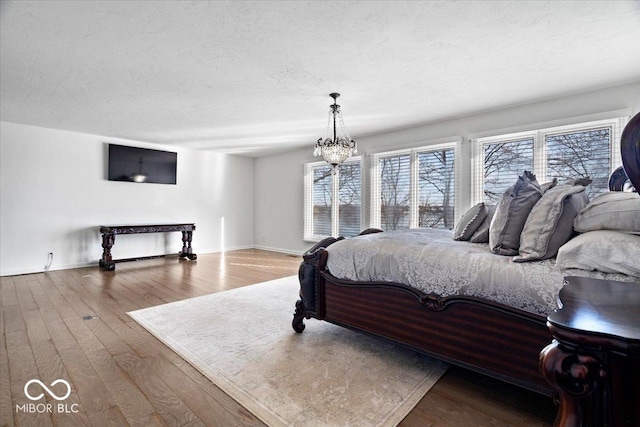 bedroom featuring a chandelier, hardwood / wood-style floors, and a textured ceiling