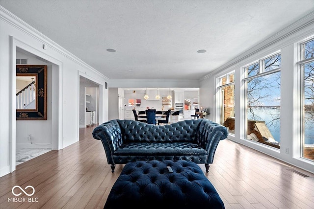 living room featuring hardwood / wood-style flooring, ornamental molding, and a textured ceiling