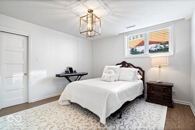 bedroom with a notable chandelier and wood-type flooring