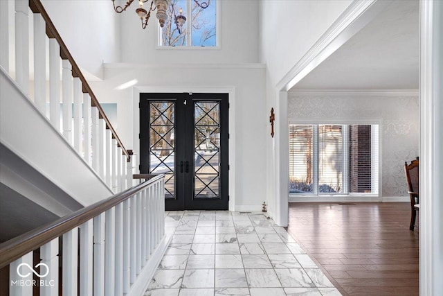 foyer featuring ornamental molding, a towering ceiling, and french doors