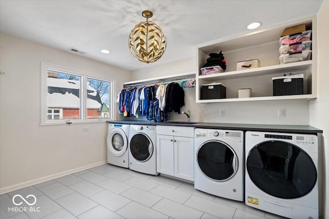 washroom with cabinets, washing machine and dryer, and sink