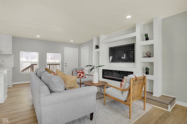 living room with built in features and light hardwood / wood-style flooring