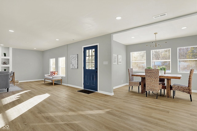 foyer with a notable chandelier, plenty of natural light, and light hardwood / wood-style floors