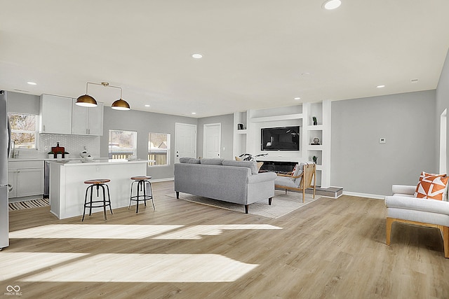 living room featuring built in shelves and light hardwood / wood-style floors