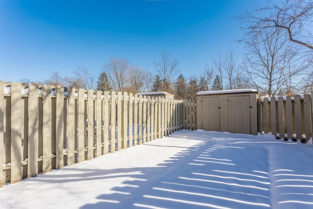 snowy yard featuring a storage unit