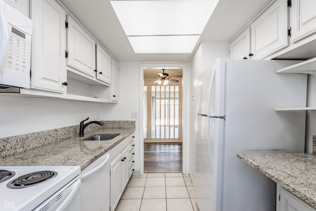 kitchen with white cabinetry, sink, light stone counters, white appliances, and light tile patterned flooring