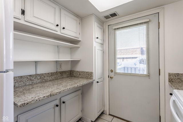 interior space with light tile patterned floors, white electric stove, white cabinetry, and light stone counters