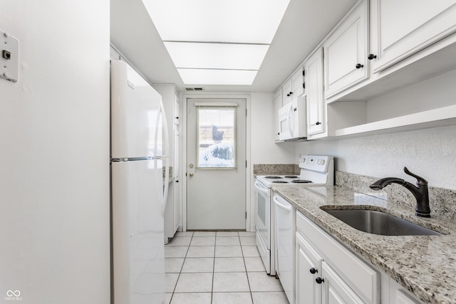 kitchen with light stone countertops, white appliances, sink, light tile patterned floors, and white cabinetry