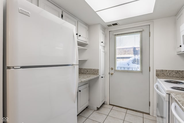 kitchen featuring white cabinetry, light tile patterned floors, light stone countertops, and white appliances