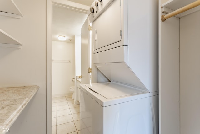 laundry area featuring light tile patterned flooring and stacked washer and dryer