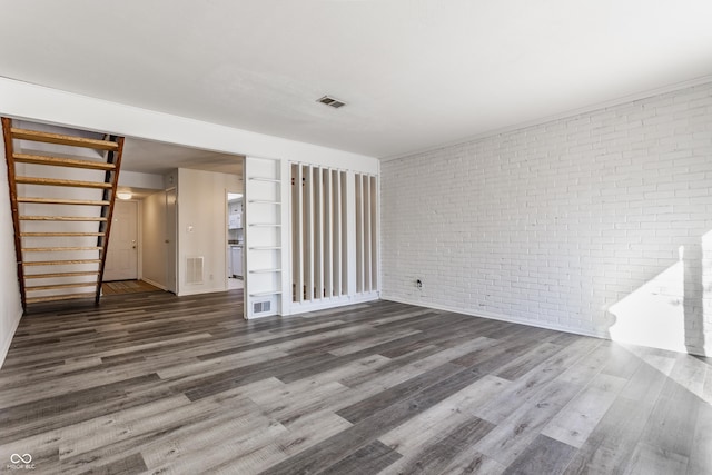 unfurnished living room featuring dark hardwood / wood-style flooring and brick wall