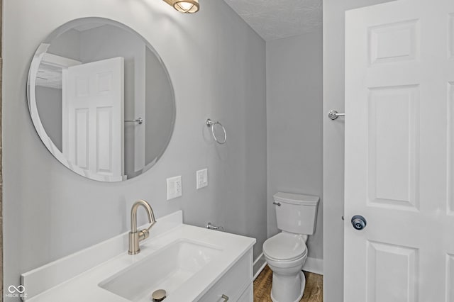 bathroom featuring vanity, toilet, a textured ceiling, and hardwood / wood-style flooring